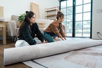 Two women rolling out a new carpet