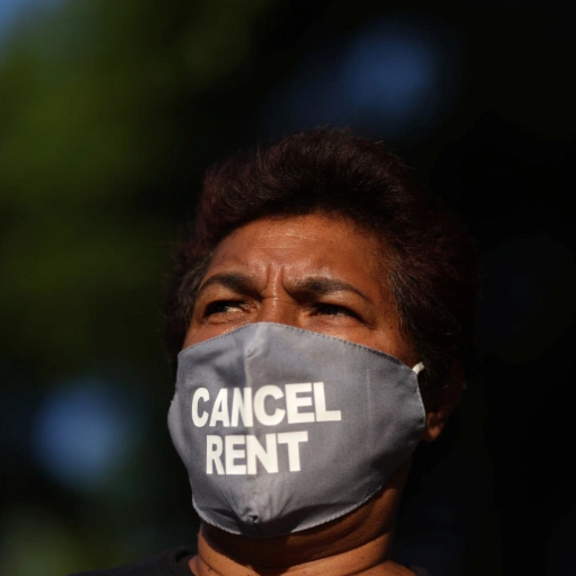 Person of color wearing a "cancel rent" face mask.