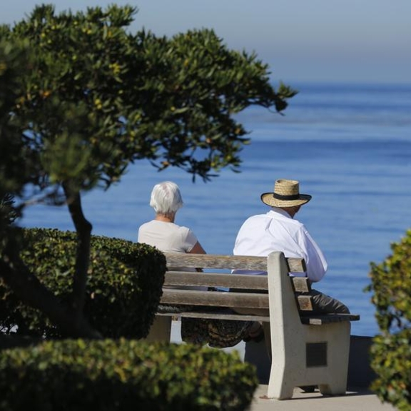 Two older adults sitting by the ocean.