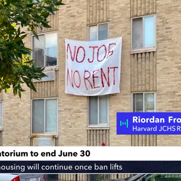 View of apartment building with "No jobs, no rent" banner hanging on it.