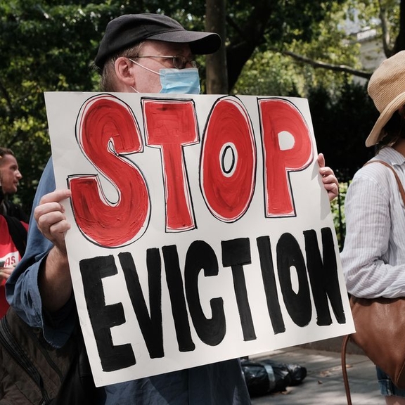 Man holding "stop eviction" sign.