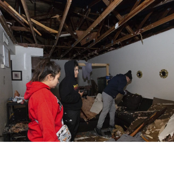 Family standing inside storm-damaged apartment.