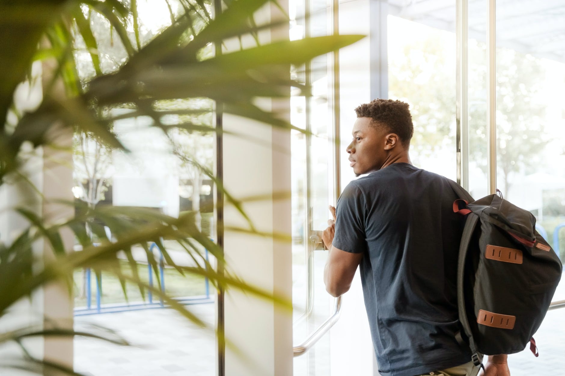 Student with a backpack walking through a door