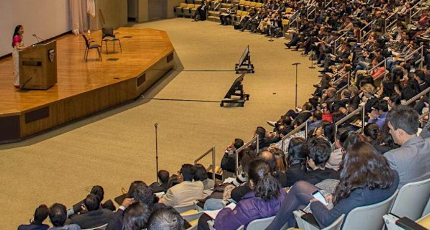 Indian woman speaking at a podium in an auditorium