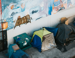 Tents on city sidewalk, with wall mural behind.