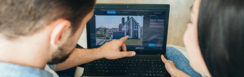 Couple pointing at real estate on laptop screen.