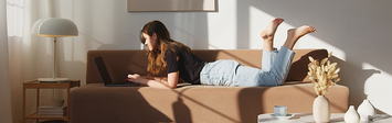Young woman working on couch in apartment.