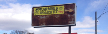 Advertisement for Brightmoor’s farmers market, in between a vacant field and a gas station.