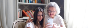 Older adult woman with granddaughter and cell phone