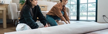 Two women rolling out a new carpet